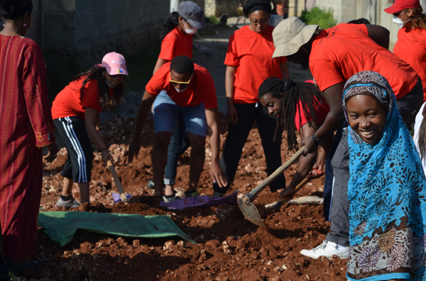 A group of students in red t-shirts digging a hole