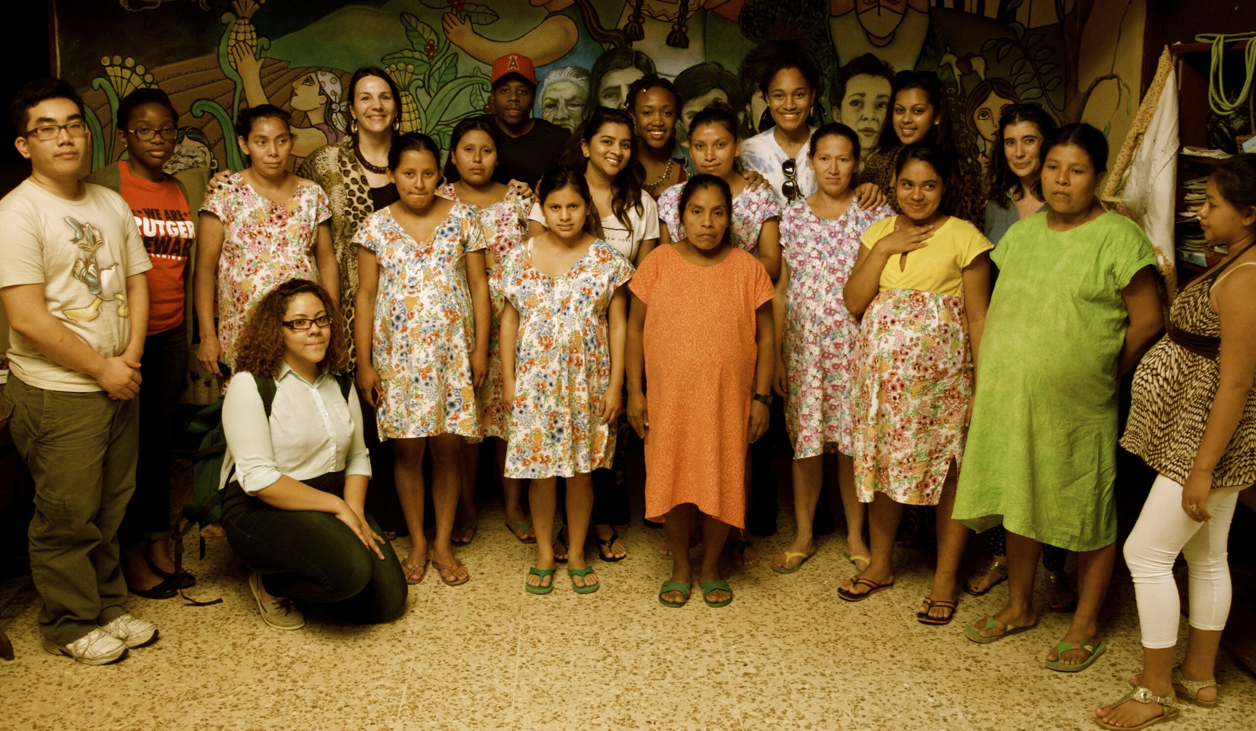 A group of primarily women of various ages and ethnicities standing in a half circle, looking at the camera