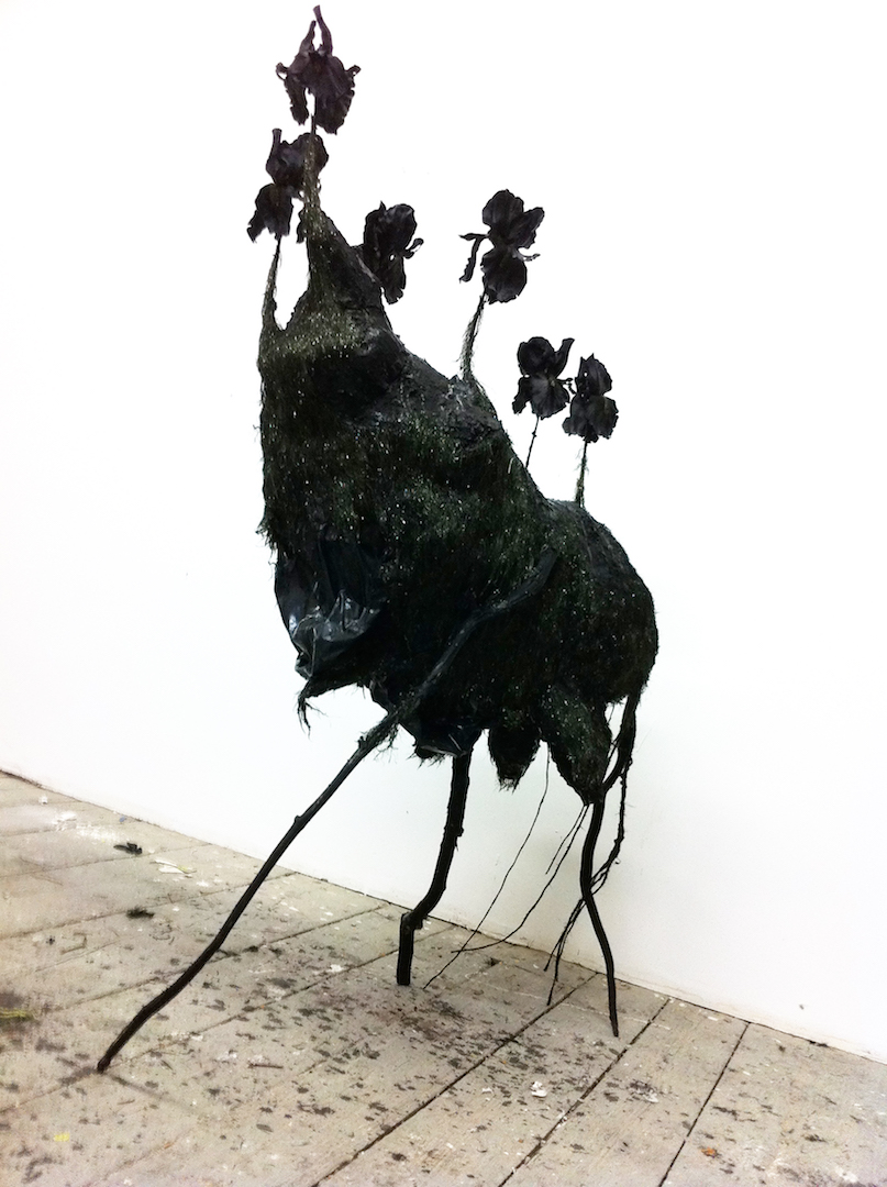 An abstract sculpture with thin legs and flowers emerging from the top