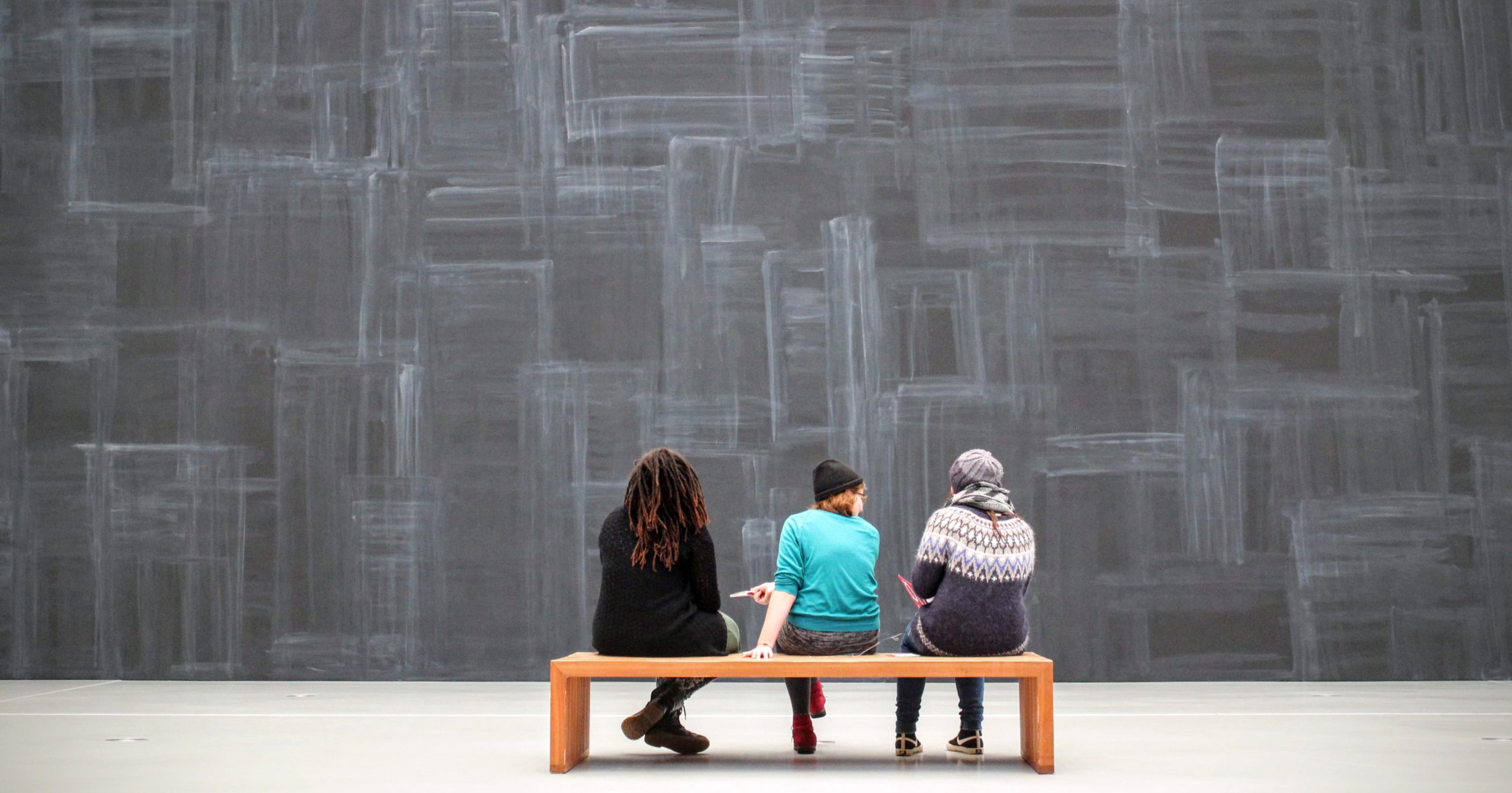 Three people site with their backs to the camera, looking at an art installation